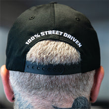 Person wearing Street Machine masthead black cap with '100% Street Driven' text